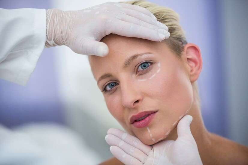 doctor-examining-female-patients-face-cosmetic-treatment_107420-74115