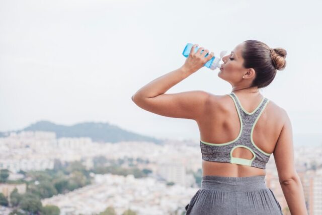 woman-drinking-water-front-city_23-2147662207